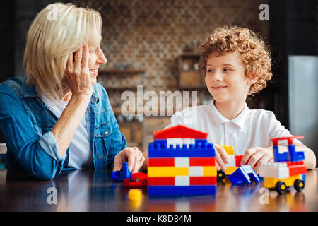 Smart curly haired kid spending time with grandmother Stock Photo