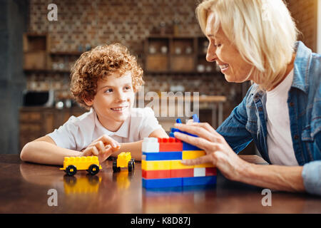 Curly haired boy talking with grandma at table Stock Photo