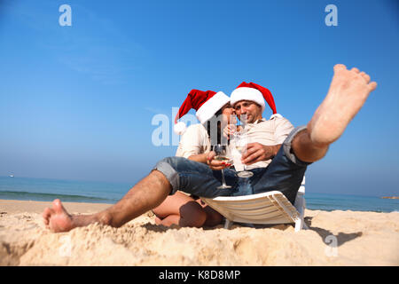 Christmas couple on a beach drinking vine Stock Photo