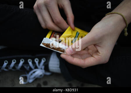 A close up of a young man starting the process of rolling a cigarette Stock Photo