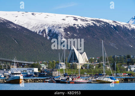 View across boats moored in harbour to Arctic Cathedral on mainland in summer. Tromso, Troms, Norway, Scandinavia Stock Photo