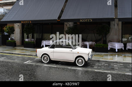 A cute small white car outside Scotts restaurant in London England Stock Photo