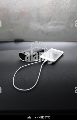 Iphone 5s with external battery charger on dash board of car Stock Photo