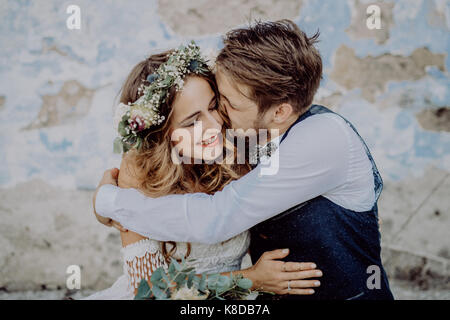 Beautiful bride and groom in front of old shabby house. Stock Photo