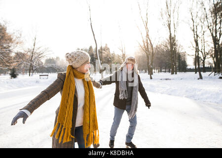 Senior couple in sunny winter nature ice skating. Stock Photo