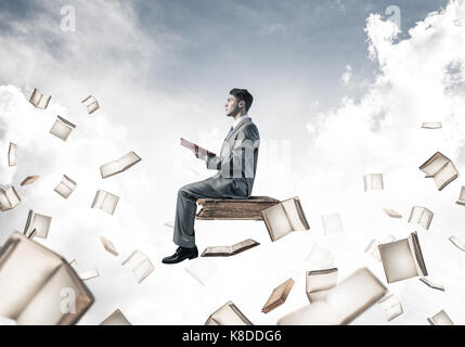 Man reading book and many of them flying in air Stock Photo