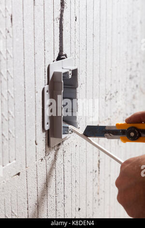 An electrician cutting through electrical wire after installing an electrical utility box into insulated concrete form in Ontario, Canada. Stock Photo