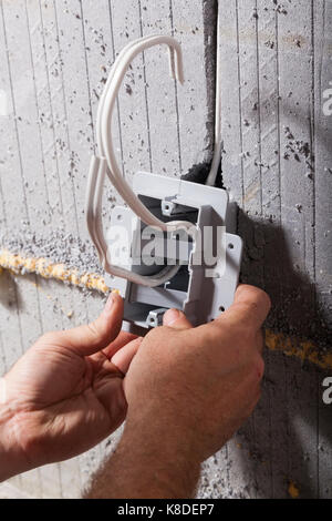 An electrician installing an electrical utility box into insulated concrete form in Ontario, Canada. Stock Photo