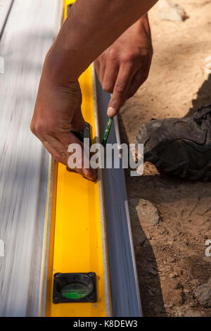 A construction worker marking vinyl siding using a pencil and a carpenter's level as a straight edge in Ontario, Canada. Stock Photo