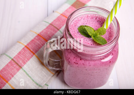 Berry milkshake or smoothie with ingredients and mint. Healthy drink in mason jar.