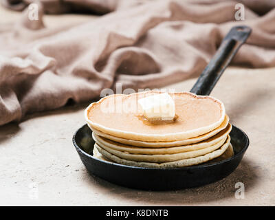 homemade pancakes with butter in iron cast. Stack of pancakes on brown concrete background. Close up. Stock Photo