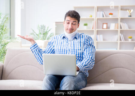 Man freelancer in a cervical collar neck brace working from home Stock Photo