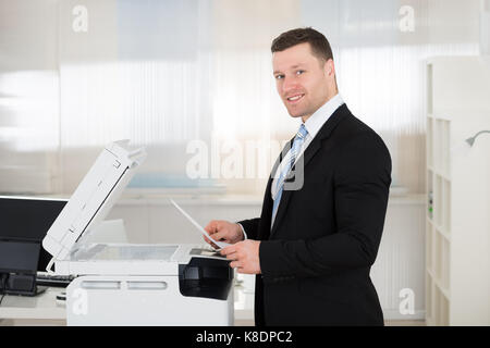 Side view portrait of businessman using photocopy machine in office Stock Photo