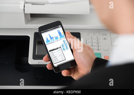 Cropped image of businessman giving print command on smart phone in office Stock Photo