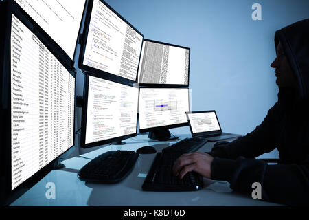 Side view of hacker using computers to steal data in office Stock Photo