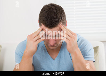 Worried mid adult man suffering from headache at home Stock Photo