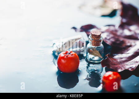 Rainy autumn still life with fallen eaves, red berries and water drops on a stone background Stock Photo