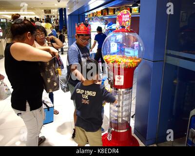 MANDALUYONG CITY, PHILIPPINES - SEPTEMBER 17, 2017: Customers of a video or amusement arcade buy gumball from a gumball machine. Stock Photo