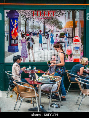 Waitress taking a lunch order from a couple at the Naschmarkt Sunday market, Vienna, Austria, against the backdrop of a large advertising billboard Stock Photo