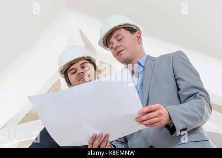 Two Engineer or Architect discuss on Modern Building Project at Construction site in Urban City Stock Photo