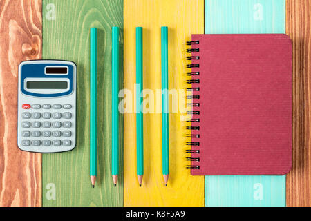 Notebook,calculator and four pencils on colored background. Stock Photo