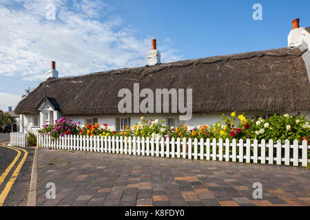 Thatched cottage with white picket fence in Churchtown, Merseyside. UK Weather. September, 2017.  Sun-loving Dahlias, which keep flowering until the first frosts arrive are in full bloom in the autumn sunshine in front of traditional old fisherman's single-storey cottage in the village. Churchtown is a tranquil, historic village on the northern fringe of Southport and dates back to the Doomsday Book. It's a designated conservation area with pretty thatched roof cottages. Stock Photo