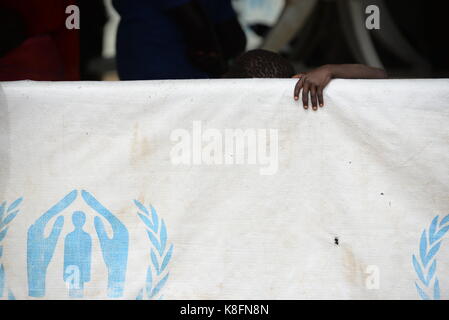Imvepi, Uganda. 27th June, 2017. A child can be seen peeking out behind a tarp of the UNHCR in the refugee settlement in Imvepi, Uganda, 27 June 2017. More than two million people have fled the civil war in South Sudan, one million of them in Uganda. Credit: Gioia Forster/dpa/Alamy Live News Stock Photo