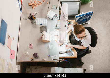 Overhead view of female jeweller at workbench Stock Photo