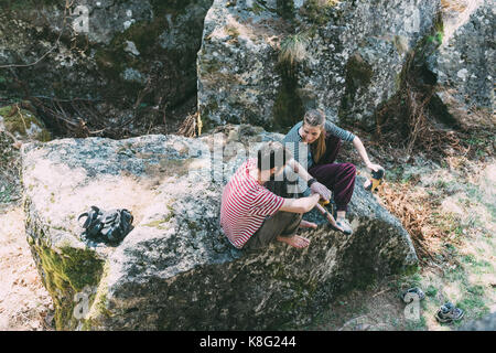 High angle view of two bouldering friends sitting on boulder, Lombardy, Italy Stock Photo