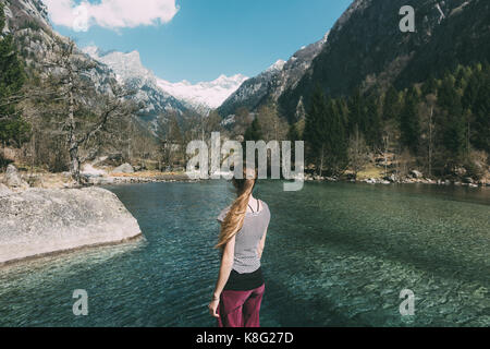 Rear view of young woman looking out over lake, Lombardy, Italy Stock Photo