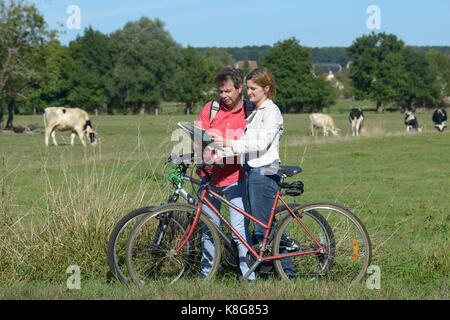 Couple of hikers riding bikes by the River Seine, on the towpath in Sahurs, town belonging to the Regional Natural Park 'Parc Naturel Regional des Bou Stock Photo