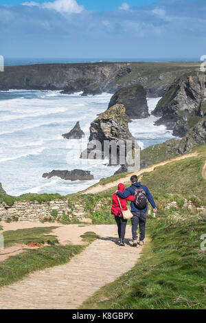 Bedruthan Steps - a couple walking and hugging each other on the South West Coast Path at Bedruthan Steps on the North Cornwall coast. Stock Photo