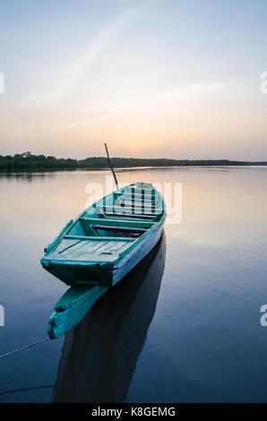 Beautiful wooden fishing boat in Gambia river during blue hour in the evening, The Gambia, West Africa. Stock Photo