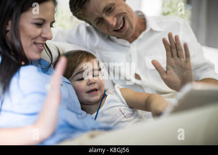 Husband and wife using digital tablet with baby girl on sofa Stock Photo