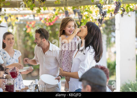 Girl feeding mother at outdoor family lunch Stock Photo