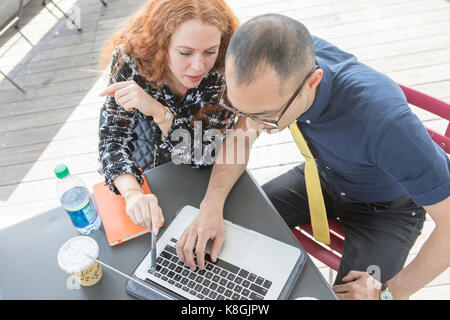 Businessman and woman using laptop at cafe table Stock Photo