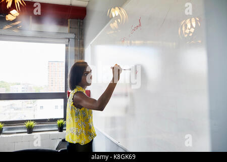 Young woman writing on whiteboard in office environment Stock Photo