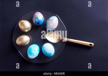 Overhead view of gold painted and dyed easter eggs on plate with gold spoon Stock Photo