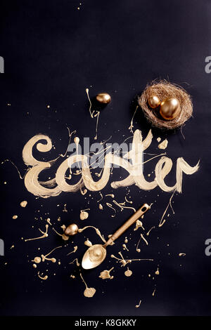 Overhead view of gold painted easter eggs with handwritten splattered easter Stock Photo