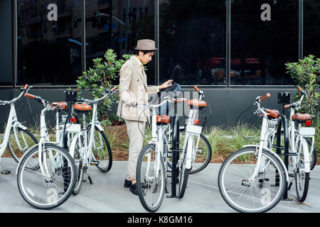 Young man preparing to use hire bicycle Stock Photo