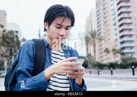 Young man outdoors, using smartphone Stock Photo