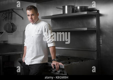 Portrait of pastry chef leaning against hob in kitchen Stock Photo