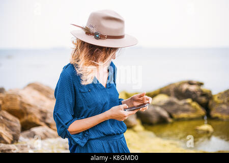 Mid adult woman in coastal setting, looking at smartphone Stock Photo