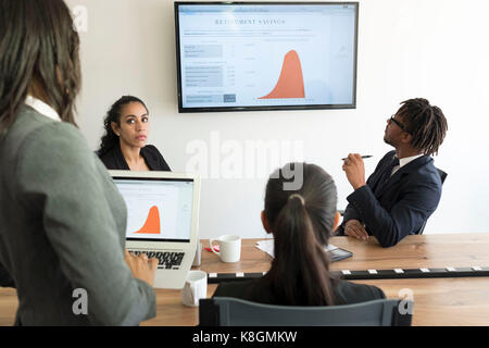 Businessman and businesswomen, in office, looking at data graphs Stock Photo