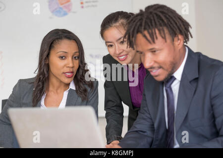 Businessman and businesswomen, in office, brainstorming, using laptop Stock Photo