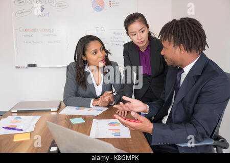 Businessman and businesswomen, in office, brainstorming, using laptop Stock Photo
