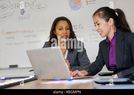 Two businesswoman, in office, looking at laptop screen Stock Photo