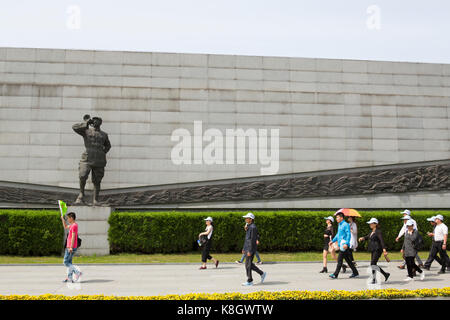 Group of Chinese visitors on guided tour passing a statue at the Nanjing Massacre Memorial, China Stock Photo
