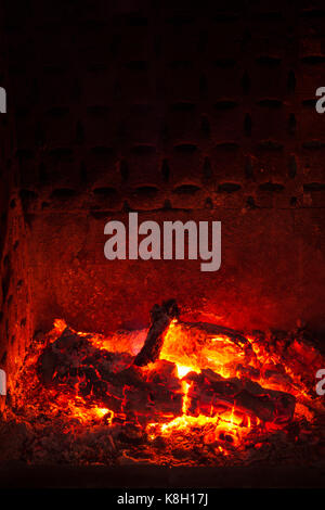 Embers with burned logs and ashes in a fireplace with warm atmosphere Stock Photo
