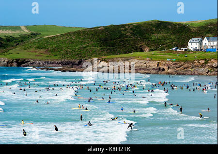 Beginner surfers and body boarders enjoying the waves at Polzeath Bay in Cornwall during the summer holidays in England. Stock Photo
